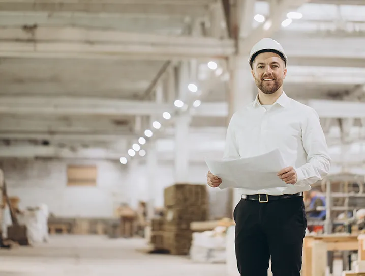 Förderkredite zur Gewerbefinanzierung, Mann mit Arbeitshelm, Lagerhalle, Finanzierungen für Unternehmen